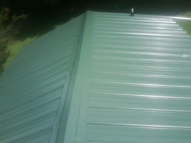 New green metal panels meeting at the ridge of a roof — Flat Roof Repair work by our crew in Hume